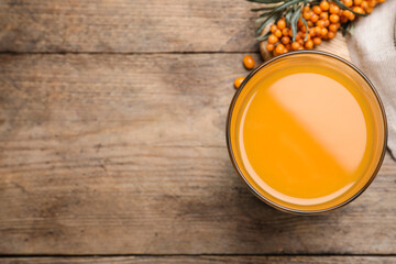 Delicious sea buckthorn juice on wooden table, top view. Space for text