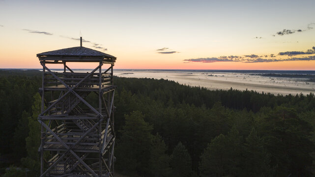 Aerial view to the wooden watchtower with the woodland and fog clad twilight bog background