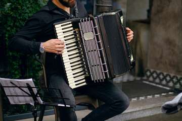 Street musician playing the accordion, stylish man cheers up with beautiful music and makes money, the concept of a free lifestyle without being tied to the main workplace