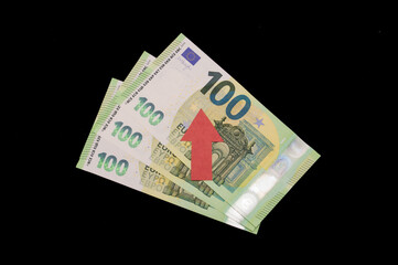 tree hundred euro bills on a black background with a red up arrow. Rising of the EURUSD