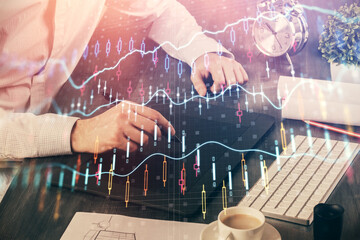 Double exposure of man's hands holding and using a phone and financial graph drawing. Analysis concept.