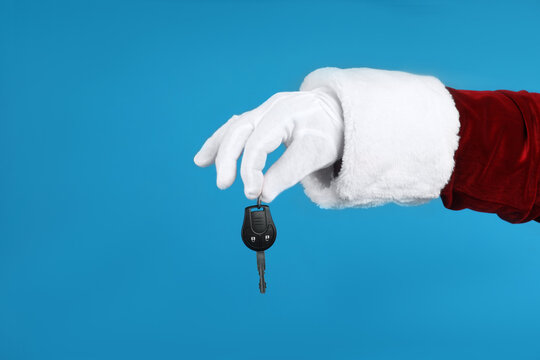 Santa Claus Holding Car Key On Blue Background, Closeup Of Hand