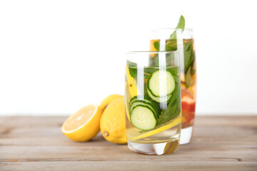Two glasses of lemon slices, cucumber slices and mint leaves infused beauty water and fresh lemon fruit on the table