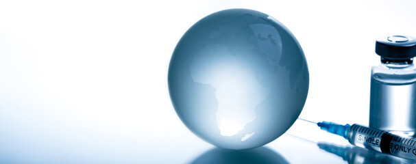 Medical syringe with a needle and a bollte with vaccine on world map.