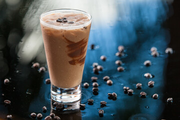 Iced coffee cocktail and coffe beans on blue background