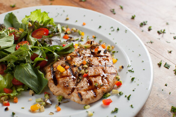 Grilled chicken with green salad and sweet cherry on wooden table
