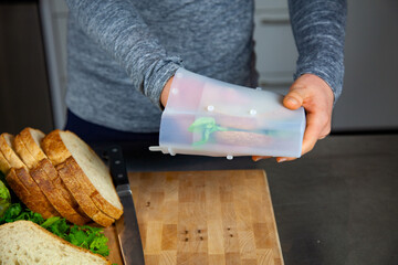 A women prepares lunch and puts a sandwich into a food-grade silicone bag as part of a zero-waste lifestyle to replace plastic bags