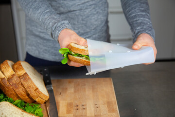 A women prepares lunch and puts a sandwich into a food-grade silicone bag as part of a zero-waste lifestyle to replace plastic bags