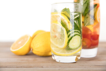 Two glasses of lemon cucumber mint water and freshly cut lemon fruit