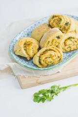 Home made buns with garlic, green parsley and sweet pepper in a plate with napkin and wooden cutting board white background.
