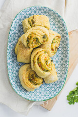 Home made buns with garlic, green parsley and sweet pepper in a plate with napkin and wooden cutting board white background.