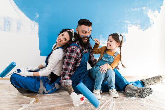 Happy family renovating their home. They are painting a wall together.