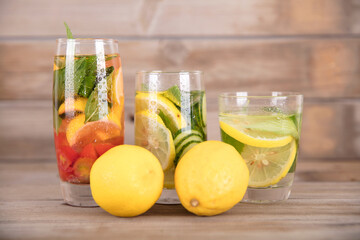 Three glasses of lemon mint water and two fresh lemon berries