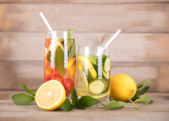 Two glasses of iced lemon mint tea and fresh lemon fruit and mint leaves next to the cup