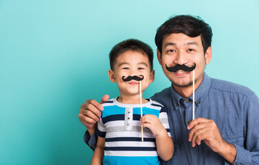 Family funny happy hipster father and his son kid holding black mustache props for the photo booth...