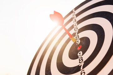 Dart arrow hitting to center on bullseye (bull's-eye) dartboard is the target of purpose challenge business at sunset, expert marketing strategy target, objective financial and goal success