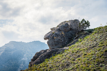 A huge stone on the mountain, resembling the head of a fairy-tale evil old woman against the background of a stormy sky