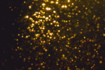 Gold bokeh from light in water with black background