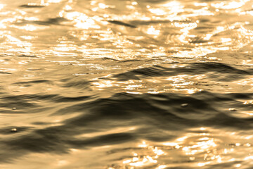 Water surface with moving wave of golden water reflecting .