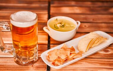 Glass of beer, chips and snacks with guacamole on rustic wooden background. Appetizer with green guacamole with mug or pint of ale. close up, 