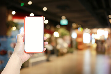 Hand of a man holding smartphone device in the Shopping mall background.