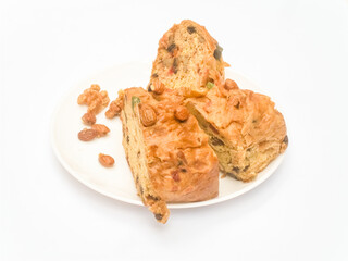 Slices of Christmas sweet bread with almonds, raisins, nuts, dry fuits on a plate on white background 