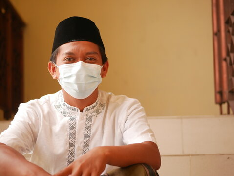 Potrait Of Indonesian Young Man With Face Mask In Mosque. Asian Man With Wearing Cloth Face Masks For Eid Mubarak / Ied Fitr. Indonesian Moslem With Face Mask During Pandemi.