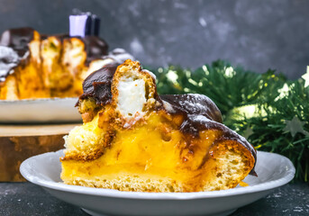 Cut piece of cake
A slice of chocolate cake with profiteroles, custard in a white saucer, christmas decor on a dark background, close-up side view.