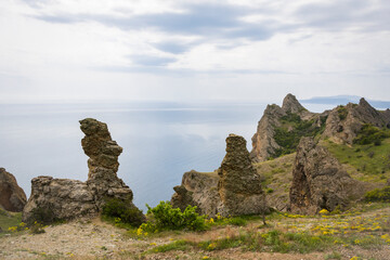 Fototapeta na wymiar View of the rocks of the Kara-Dag mountain range against the sea and cloudy sky on the Crimean Peninsula