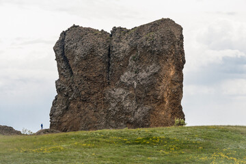 A huge rock of cubic shape on a green mountain valley