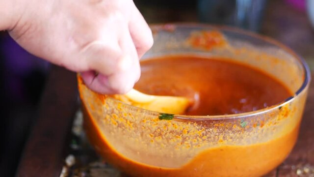 A Indonesian woman watery sambal pecel (peanut sauce) in a glass. Preparing sambal pecal.