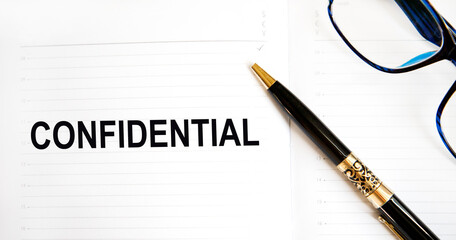 Text in THE CONFIDENTIAL notebook, next to glasses and pen.