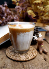 Dirty coffee or milk coffee, top with coffee shot on a wooden table, flower background.