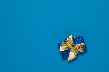 Blue box with a gift in a gold ribbon on a blue background.