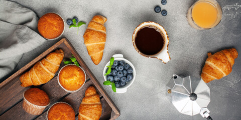 Continental breakfast captured from above (top view, flat lay). Coffee,  juice, croissants,muffins and blueberry.