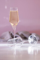 champagne glass next to a lying down empty glass of champagne on an out of focus background