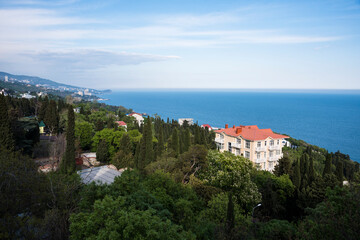 View of the slope of the mountain covered with forest and buildings of the city of Alupka on the Crimean Peninsula against the Black Sea