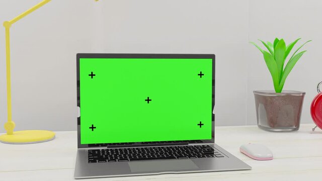 Laptop with green screen on table Work desk in office and RED Alarm clock, mock-up for your text. 3d render.