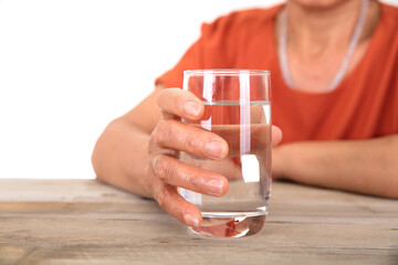 An old Chinese lady holding a glass of water in front of a white background