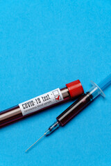 Syringe And Plastic Test Tube With Blood Sample over blue background with copyspace