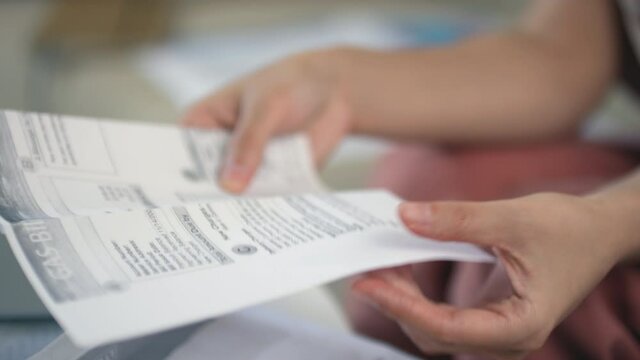 Closeup of unrecognizable female hands unfolding letter containing payment information, unpaid bills and taxes