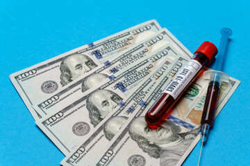 Close up 100 US dollar bills and blood sample in test tube over blue background