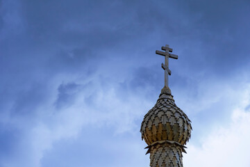 Wooden chapel's dome with orthodox cross on the top with cloudy sky background. Religious symbol. Faith concept.