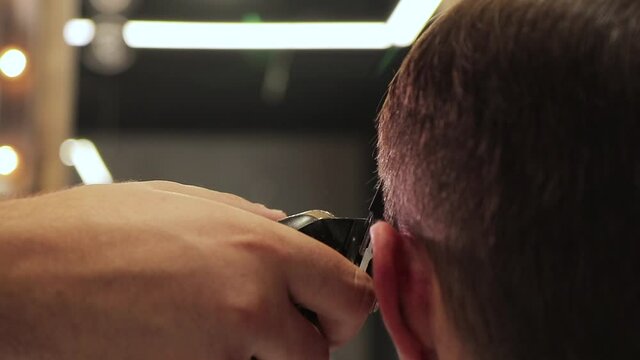 barber cuts a man's hair with a shaving machine