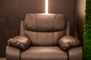 Comfortable armchair made of brown leather and placed in corner of cozy lounge room