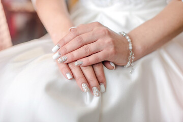 Obraz na płótnie Canvas Hands of the bride on a white wedding dress