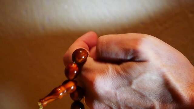 Close-up of an old man's hand fingering beautiful brown rosary