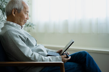タブレットPCを見る日本人シニア男性 © arc image gallery
