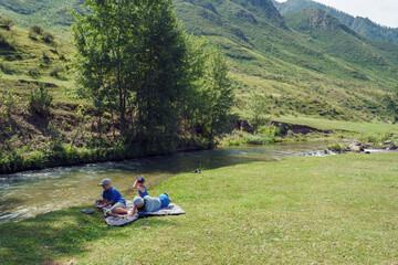Fototapeta na wymiar family resting on the beach of mountain river