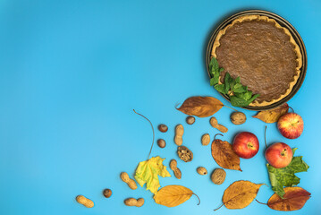 Beautiful Thanksgiving creative background of pumpkin pie with fresh min leaves, nuts, apples, autumn leaves, and cloves on light blue background. Man cooking. Copy space. Dublin, Ireland